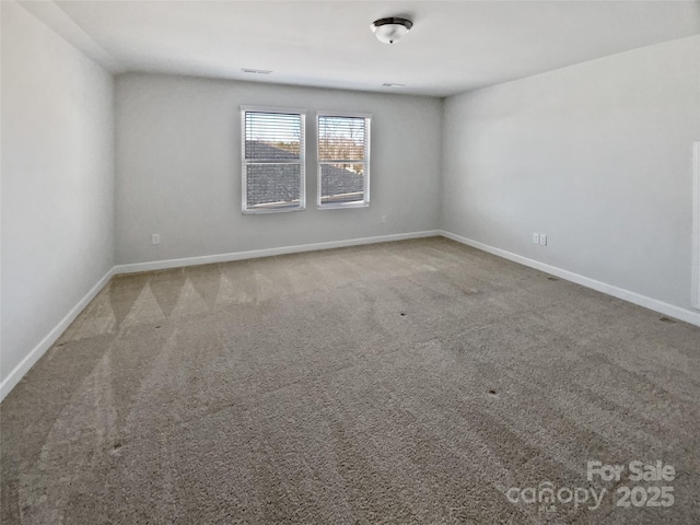 carpeted spare room featuring visible vents and baseboards