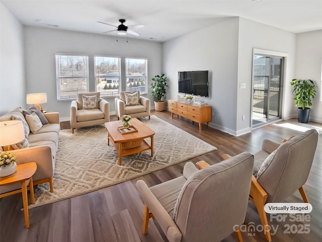 living area with baseboards, a ceiling fan, and wood finished floors