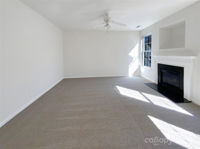 unfurnished living room featuring visible vents, baseboards, carpet floors, ceiling fan, and a glass covered fireplace