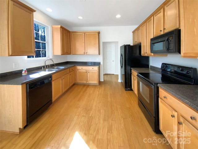 kitchen featuring dark countertops, black appliances, light wood-type flooring, and a sink