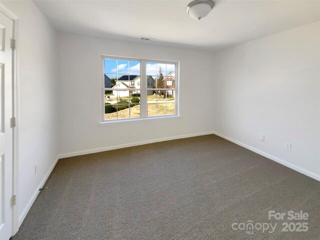 unfurnished room with visible vents, baseboards, and dark carpet