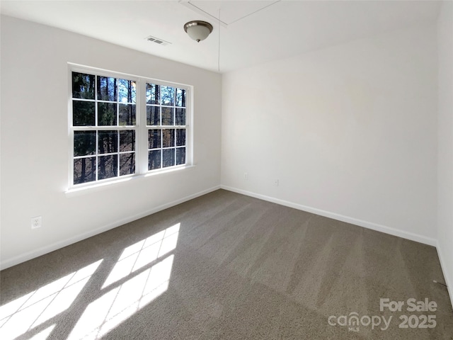 carpeted spare room featuring visible vents, attic access, and baseboards