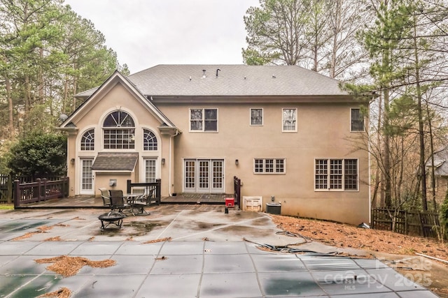 rear view of property featuring stucco siding, a patio, fence, french doors, and central AC unit