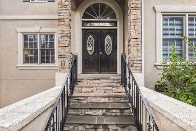 view of exterior entry featuring stone siding and stucco siding