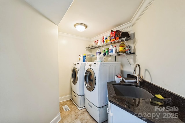 clothes washing area with visible vents, ornamental molding, laundry area, washer and dryer, and a sink