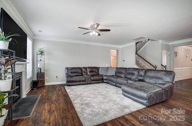 living area with stairway, wood finished floors, a ceiling fan, visible vents, and a fireplace with raised hearth