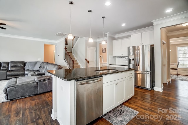 kitchen with visible vents, open floor plan, dark stone counters, stainless steel appliances, and a sink