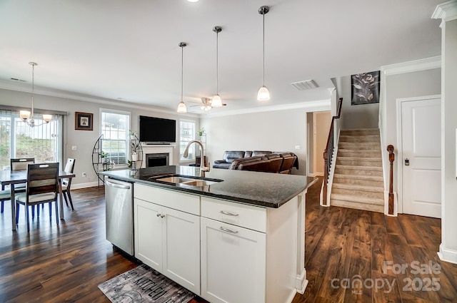 kitchen featuring visible vents, a sink, stainless steel dishwasher, an inviting chandelier, and a fireplace