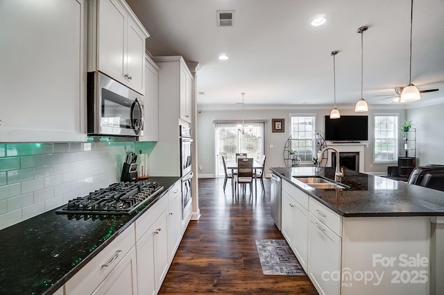 kitchen featuring visible vents, backsplash, open floor plan, appliances with stainless steel finishes, and a sink