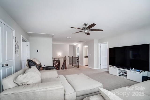 living room featuring attic access, light colored carpet, baseboards, and ceiling fan