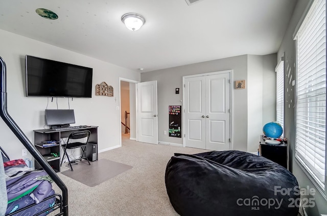 carpeted bedroom with a closet and baseboards