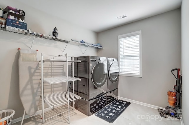 laundry room featuring tile patterned floors, visible vents, washing machine and dryer, baseboards, and laundry area