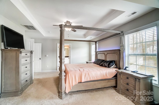 bedroom featuring visible vents, light colored carpet, a tray ceiling, and ornamental molding