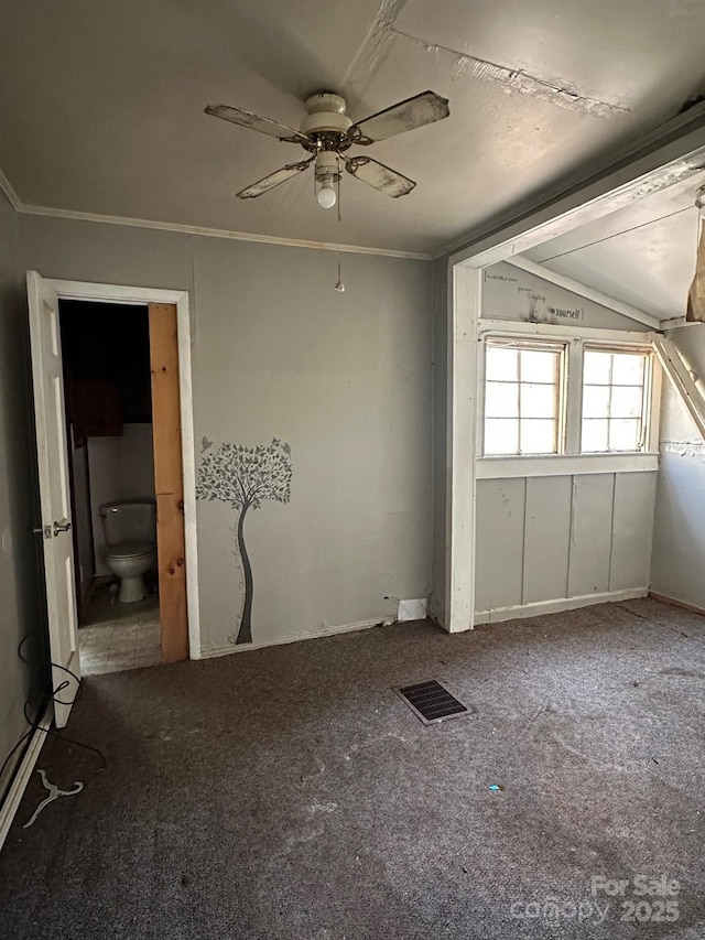 carpeted empty room with visible vents, crown molding, ceiling fan, and vaulted ceiling