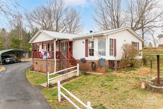 view of front of house featuring driveway, covered porch, a carport, a front lawn, and metal roof