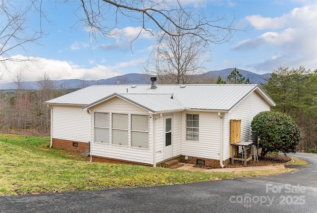 back of house featuring crawl space, a lawn, a mountain view, and metal roof