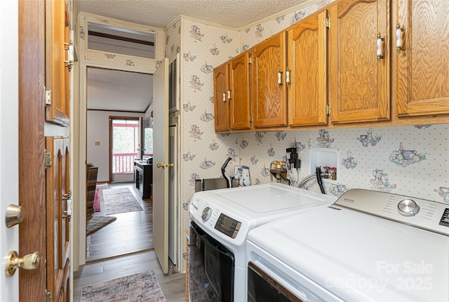 laundry room featuring cabinet space, washing machine and dryer, a textured ceiling, and wallpapered walls