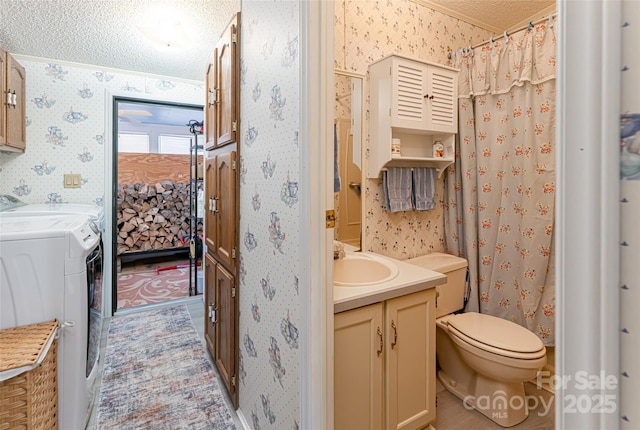 ensuite bathroom with toilet, independent washer and dryer, a textured ceiling, wallpapered walls, and vanity