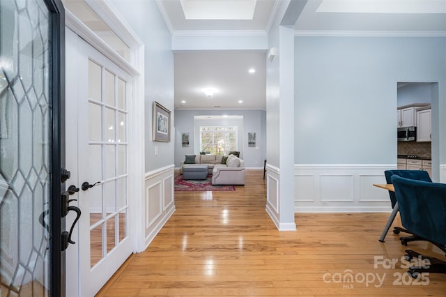 entrance foyer with a decorative wall, light wood-style floors, and ornamental molding