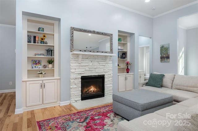 living room with crown molding, built in shelves, light wood-style floors, and baseboards