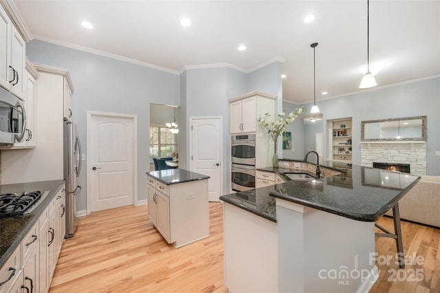 kitchen with a breakfast bar, a sink, light wood-style floors, appliances with stainless steel finishes, and a center island