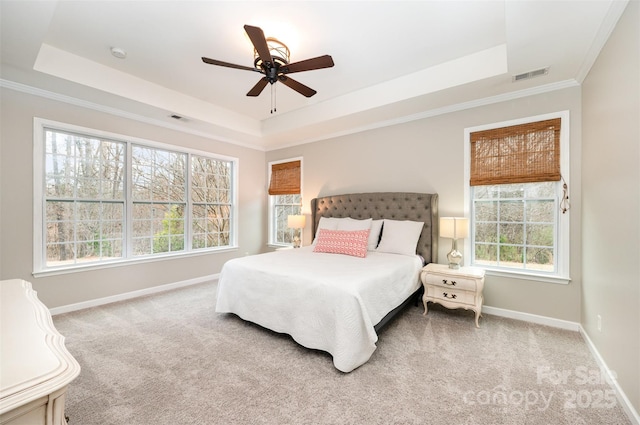 carpeted bedroom featuring a tray ceiling, baseboards, and visible vents