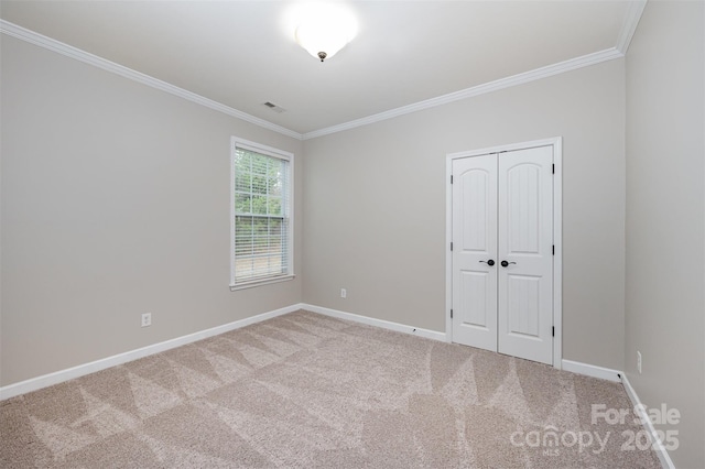 unfurnished bedroom featuring visible vents, baseboards, ornamental molding, and carpet flooring