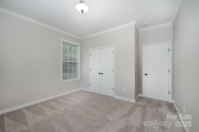 unfurnished bedroom with a closet, ornamental molding, baseboards, and carpet floors