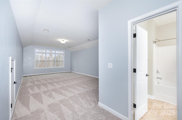 spare room with visible vents, light colored carpet, baseboards, and lofted ceiling