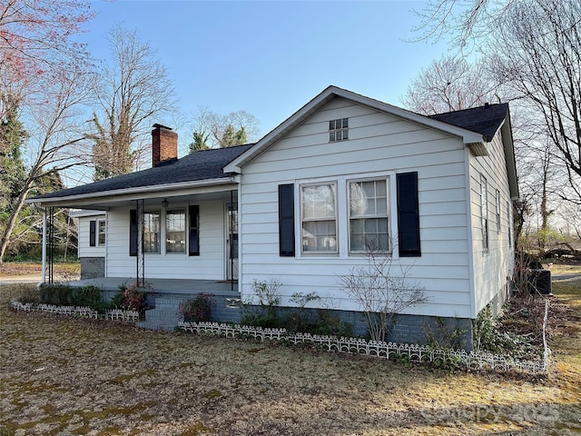 bungalow with roof with shingles, covered porch, and a chimney