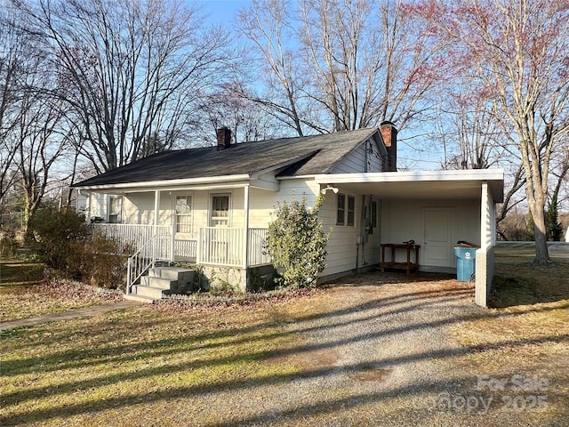 view of front of home featuring an attached carport, a porch, gravel driveway, and a chimney