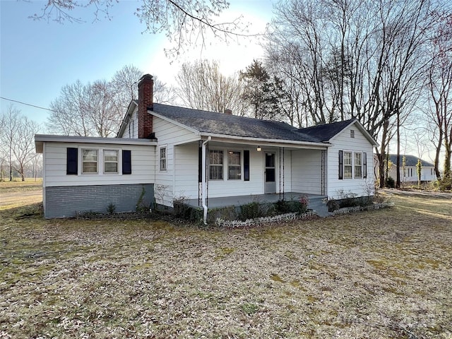 ranch-style house featuring a porch and a chimney