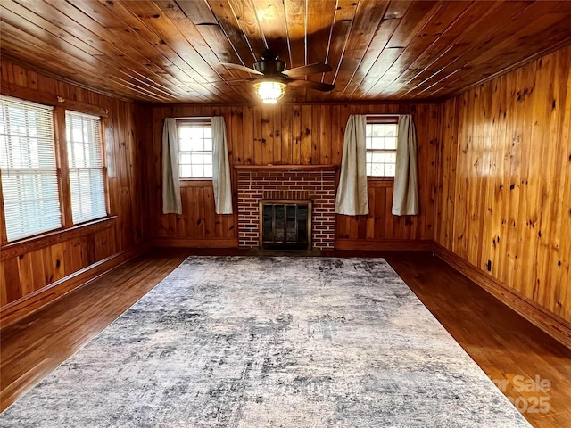 living area featuring a fireplace, wood ceiling, and wood finished floors