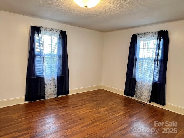 spare room with baseboards, a textured ceiling, and wood finished floors