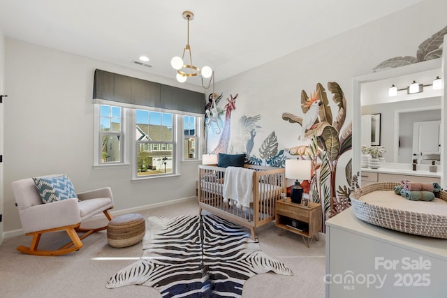 carpeted bedroom featuring baseboards, visible vents, a crib, and an inviting chandelier