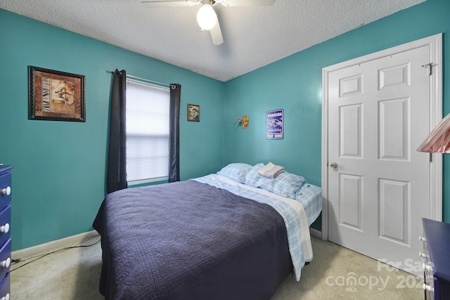 bedroom featuring baseboards, light colored carpet, a textured ceiling, and ceiling fan