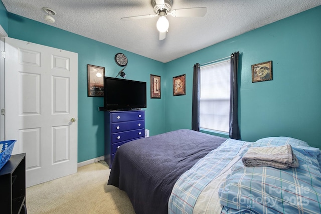 bedroom with baseboards, light colored carpet, a textured ceiling, and a ceiling fan