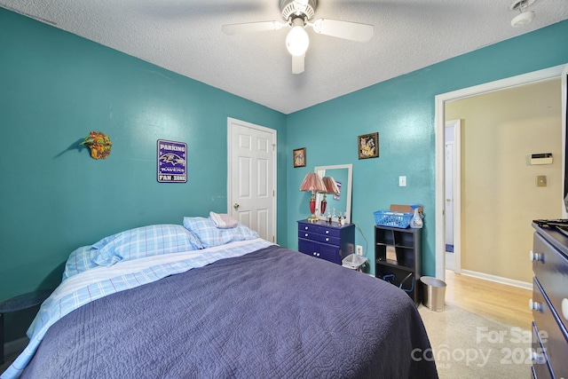 bedroom featuring baseboards, a textured ceiling, and a ceiling fan