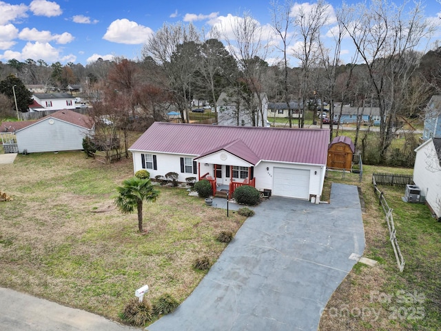 view of front of home with a garage, concrete driveway, metal roof, and a front lawn