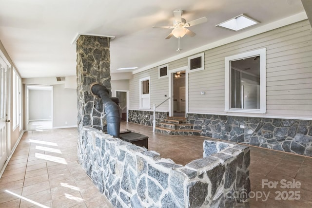 3607 Austin Rd, Monroe, NC 28112 - living area with tile patterned floors, visible vents, a wood stove, and a ceiling fan