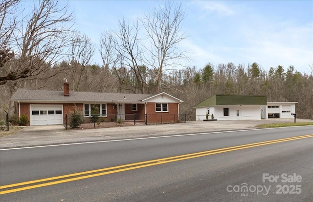 ranch-style home with a fenced front yard, brick siding, and a chimney