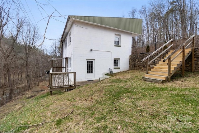 back of property featuring stairway and a lawn