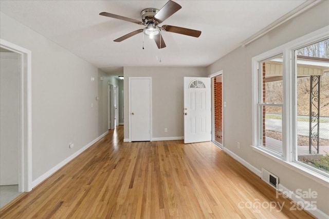 interior space featuring multiple windows, baseboards, visible vents, and light wood finished floors