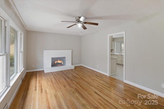 unfurnished living room with visible vents, baseboards, light wood-style floors, and a brick fireplace