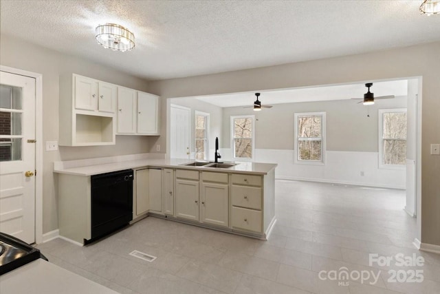 kitchen with a sink, black dishwasher, a peninsula, and light countertops