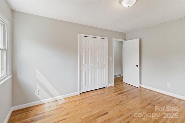 unfurnished bedroom with visible vents, multiple windows, and light wood-style flooring