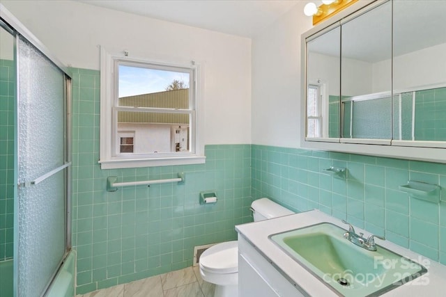 full bathroom with vanity, bath / shower combo with glass door, tile walls, toilet, and marble finish floor