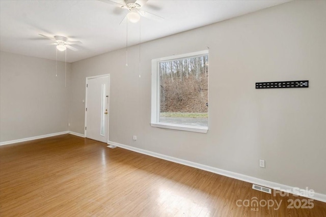 spare room with baseboards, wood finished floors, visible vents, and ceiling fan