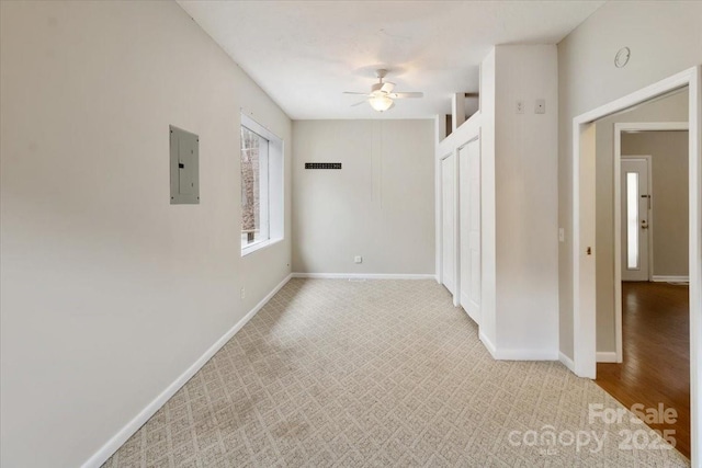 unfurnished room featuring electric panel, a ceiling fan, and baseboards