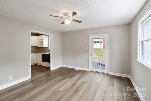 empty room featuring baseboards, a textured ceiling, wood finished floors, and a ceiling fan